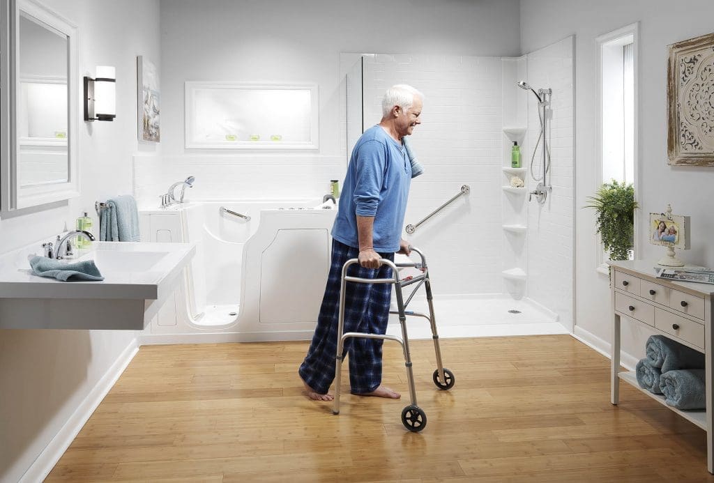 Older adult using a walker in a bright accessible bathroom with a walk-in tub