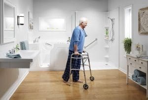 Older adult using a walker in a bright accessible bathroom with a walk-in tub