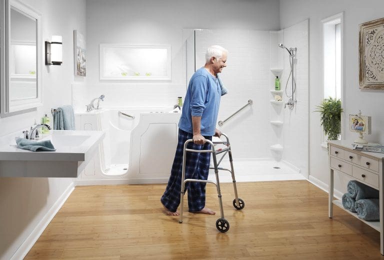 Older adult using a walker in a bright accessible bathroom with a walk-in tub