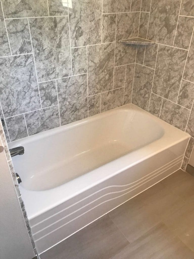 White bathtub with gray Arctic Ice stone-look wall surround