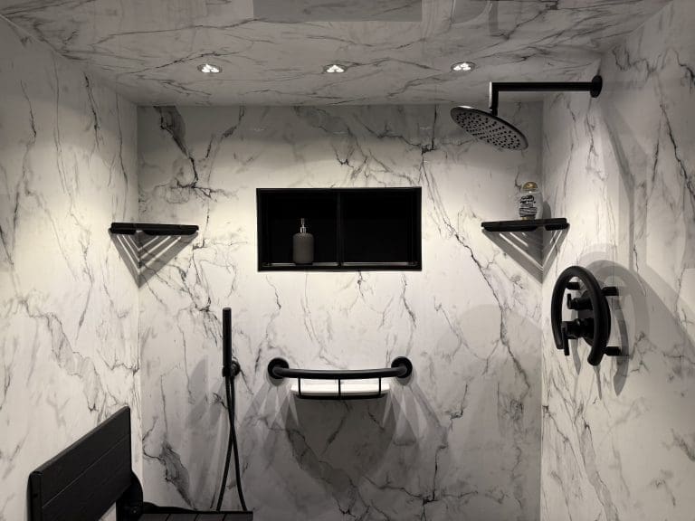 Walk-in shower with white marble-look walls, matte black fixtures, shelves, and seat