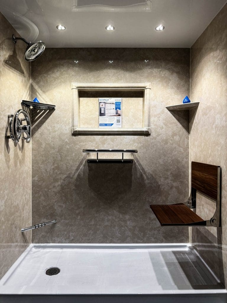 White Travertine walk-in shower with black fixtures, shelves, grab bar, and seat